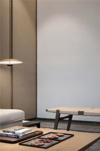 A modern living room featuring a wooden table with rope woven seat, a pendant light, and a minimalist aesthetic