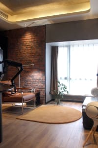 Modern living room with a brick accent wall, wooden floor, and a large window.