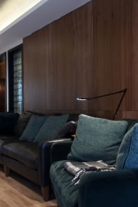 Modern minimalist living room featuring black leather couches, green velvet armchairs, and green cushions with a black readin