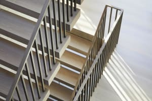 A modern wooden staircase with black metal railings.