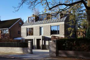 Modern brick and concrete exterior of a house with large windows and a metal roof.