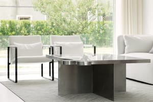 A modern living room with white furniture and a metal coffee table in front of a window.
