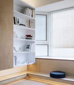 Modern interior design featuring a white wooden shelving unit with books, a sculpture, and a small figurine.