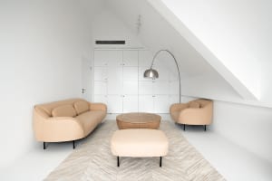 A modern minimalist living room with a beige sofa, two beige armchairs, a round wooden coffee table, and a tall floor lamp in