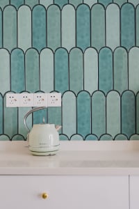 A modern kitchen with a white countertop and blue ceramic tiles on the wall.