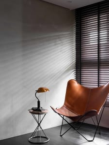 An industrial living space featuring a leather butterfly chair and a metal table lamp.
