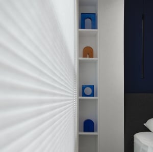Modern bedroom with white minimalist shelves, blue and orange geometric objects, and a dark headboard.