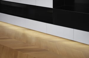 Modern living room featuring a wood floor with geometric patterns and white storage units.