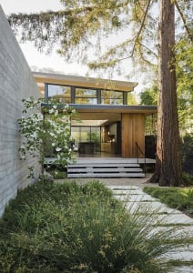 A modern residential house with a combination of concrete, wood, and glass materials.