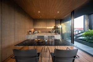 A modern residential kitchen featuring a marble countertop with stainless steel appliances and black chairs.