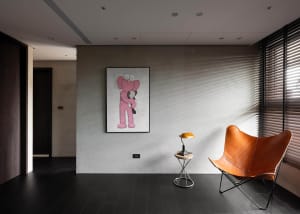 A modern living room with a concrete wall, featuring a large piece of artwork depicting a pink bear holding a smaller bear.