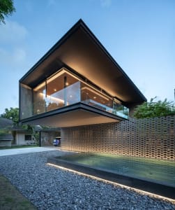A modern house exterior featuring glass walls, concrete structure, and metal accents.
