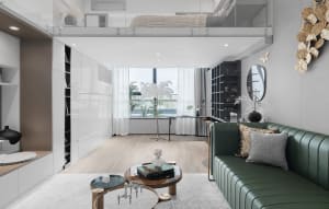 Modern living room with wood flooring and minimalist furniture, featuring a green sofa, round glass tables, and a sleek, cont