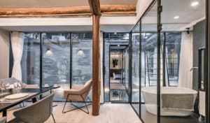 Modern dining room with glass walls and a wooden floor, showcasing minimalist industrial design elements.