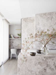 A minimalist living room with a marble accent wall and decorative elements.