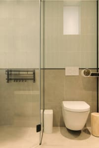 A modern minimalist bathroom with white tiles and a white toilet.