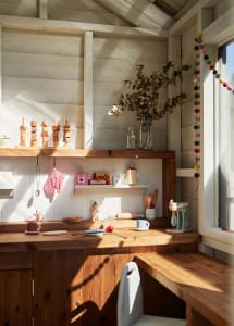 A play kitchen with wooden shelves, wooden blocks, and various toy cooking items.