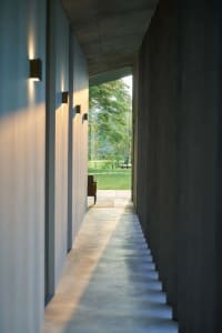 A minimalist concrete hallway leading to a garden.