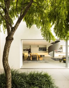 A modern minimalist living room with a white interior, spiral staircase, and large windows allowing natural light.