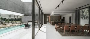 Modern residential interior featuring a concrete dining area with glass and steel accents and a backyard pool.