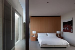 A modern bedroom with a wooden wall, white bedding, and white lamps on nightstands.