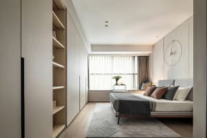 A modern minimalist bedroom featuring neutral tones and a tidy, organized space.
