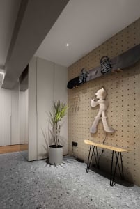 A modern entryway with wood pegboard, skateboard, and plant.