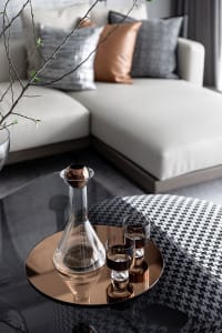 Modern minimalist living room with glass vase and two glasses on a metallic table.