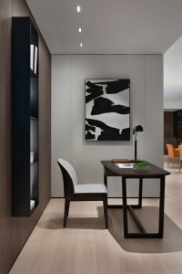 A modern industrial home office with a wooden desk and chair, a black and white abstract painting, and a built-in floating sh