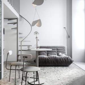 A minimalist living room with a gray sofa, a white round table, two white chairs, and a spiral staircase with a white hanging