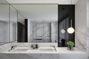 Modern bathroom with marble sinks, white countertops, and black accents.