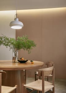 A modern dining room featuring wooden furniture with a round table and chairs, illuminated by a pendant light and enhanced wi