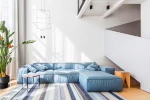 A modern living room featuring a blue sofa, a white coffee table, and a striped rug
