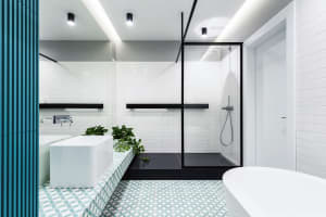 Modern bathroom with white subway tiles, black accents, and geometric patterned floor tiles.