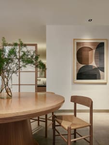 A modern dining room with a wooden table, chairs, and a plant in a vase.