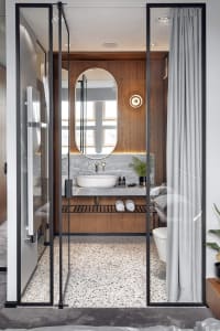 Minimalist, modern bathroom with marble sink, wood vanity, and frosted glass shower doors.