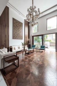 Modern living room with a white sofa, teal chairs, and a geometric wooden floor.
