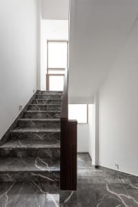 Modern staircase with marble steps and a wooden handrail.