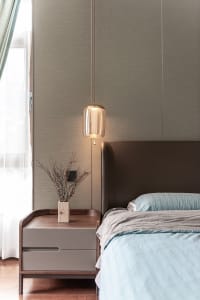 Modern minimalist bedroom with light blue bedding, wooden nightstand, and green foliage on the nightstand.