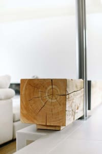 A minimalistic wooden block with rings and cracks on a white surface.