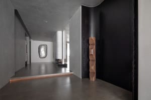 A modern interior space with concrete walls and a wooden sculpture