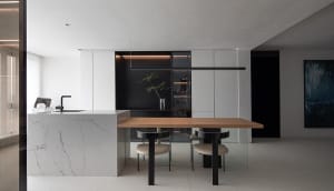 Modern minimalist kitchen with marble countertop and black cabinets.