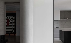 Modern interior design featuring a kitchen with marble countertops and white cabinets.