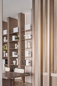 A modern bookshelf adorned with various art pieces and vases, enclosed by wooden panels with metallic accents.