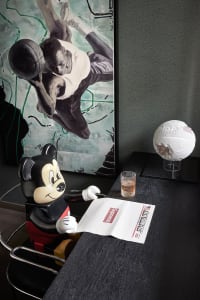 A modern minimalist interior featuring a black and white theme with a Mickey Mouse figurine holding a newspaper, a basketball