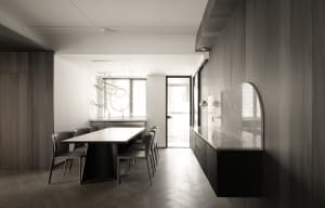 Modern residential dining room featuring wooden-paneled walls, a marble table top, and black furniture.