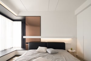 Modern bedroom with a black metallic panel headboard and light-colored bedding.