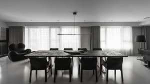 A sleek, minimalist modern dining room with a long black dining table and black chairs, featuring a long black horizontal lig