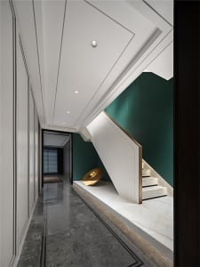 Modern, minimalist residential interior design featuring a marble staircase with a green accent wall and a minimalist art ins