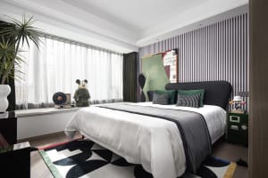 A modern bedroom interior with a white bed, green and black accents, and a striped wall.